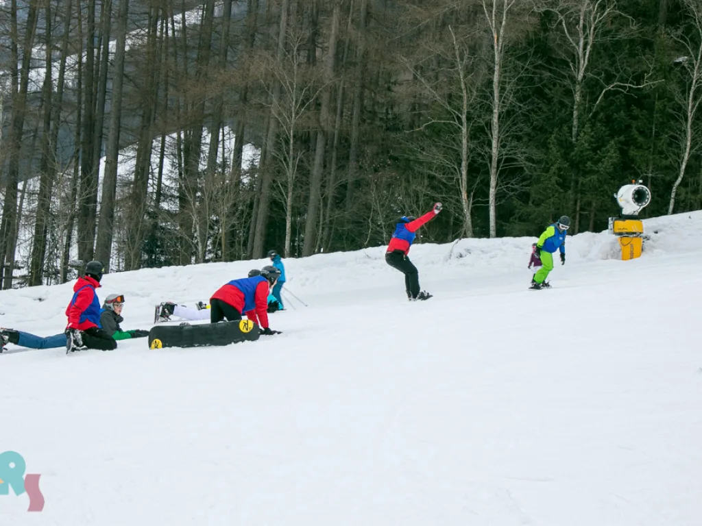 Jugendliche sitzen und liegen mit Snowboards im Schnee.